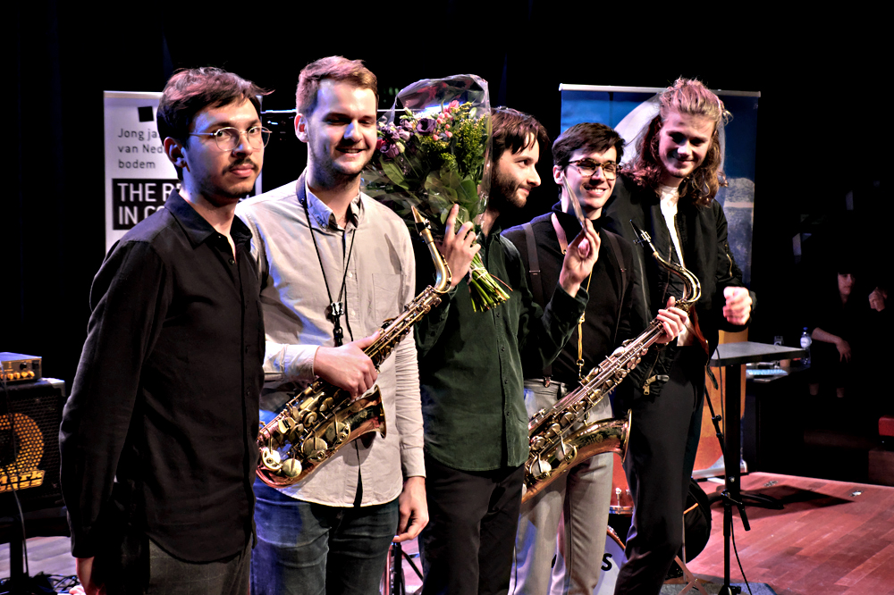 Tijs Klaassen (midden) en zijn band ontvangen bloemen na hun optreden.